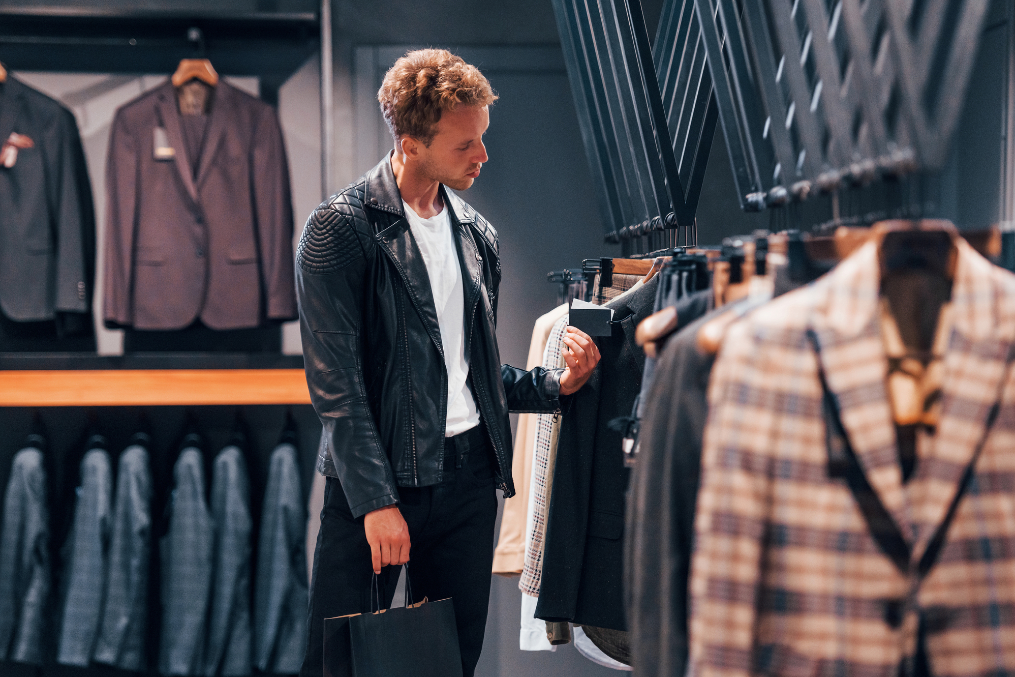 In beautiful black jacket. Young guy in modern store with new clothes. Elegant expensive wear for men Abito Monopetto Gessato